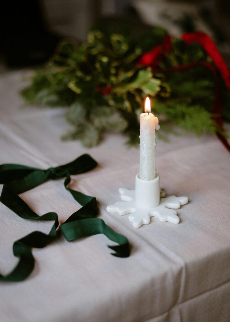 A festive candlelit table setting with greenery and red ribbons enhances holiday warmth.